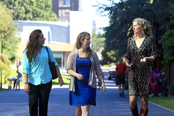 Three graduate students walking along the lower mall on campus